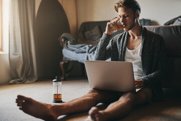 Just what I needed to start my day off. Shot of a handsome young man using his laptop while sitting on the floor at home.