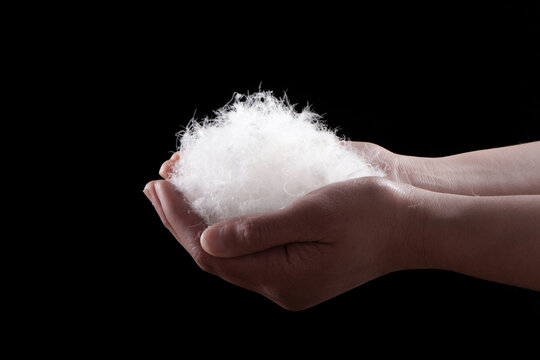 soft down feather in hand on black background