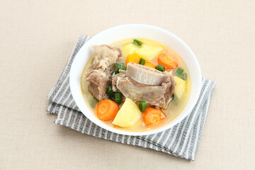 Sop Iga (Beef ribs soup) is Indonesian soup. Made from ribs, carrots, leeks, and potatoes. Served in white bowl. Selected focus
