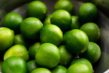 Varios limones verdes en un tazon. Concepto de frutos, naturaleza.