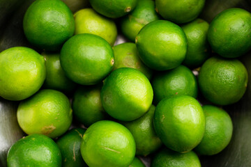 Varios limones verdes en un tazon. Concepto de frutos, naturaleza.
