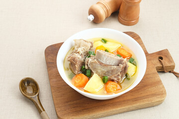 Sop Iga (Beef ribs soup) is Indonesian soup. Made from ribs, carrots, leeks, and potatoes. Served in white bowl. Selected focus
