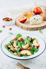 Healthy summer salad with spinach, peach, pecan nuts, blue cheese on white background