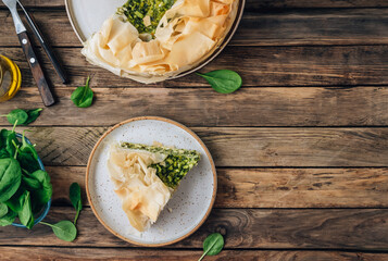 Vegetarian spinach pie with feta cheese on wooden background. Traditional Greek spinach pie Spanakopita