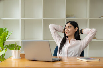 Portrait of a happy Asian woman smiling happily relaxing sitting on a chair. Independent young Asian hipster girl using laptop computer in coffee shop work-study concept