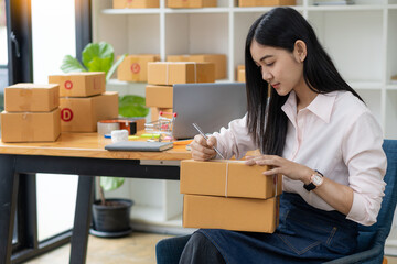 Fototapeta na wymiar portrait of an Asian woman attractive girl sme business owners starts working with laptop happily with the box at home Prepare to deliver parcels in SMEs, supply chains, online procurement concepts.
