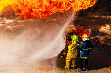 Firefighter training., fireman using water and extinguisher to fighting with fire flame in an emergency situation., under danger situation firemen wearing fire fighter suit for safety.