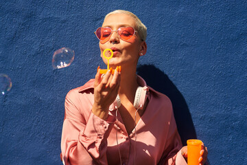 Feeling young and trendy. Cropped shot of an attractive young woman standing against a blue wall...