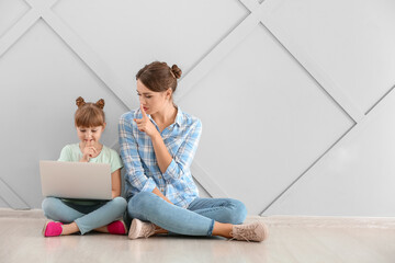 Portrait of mother and daughter with laptop showing silence gesture indoors