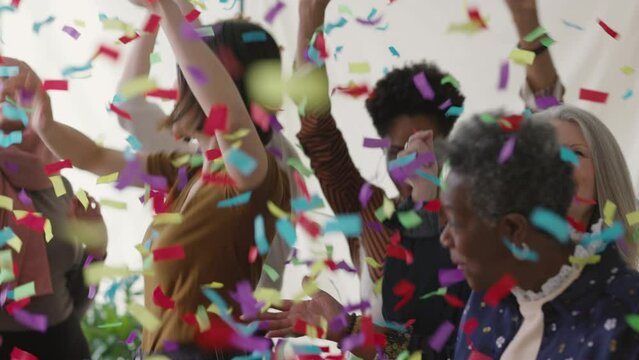 Slow motion of cheerful multi ethnic women celebrating and dancing with ticker tape falling