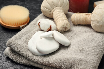 Bathing towel with spa stones and herbal bags on dark background