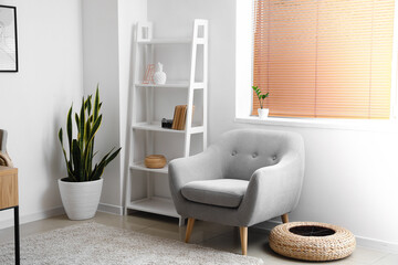Interior of light room with modern shelving unit and armchair
