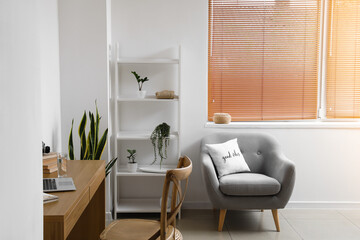 Interior of light room with modern shelving unit and armchair