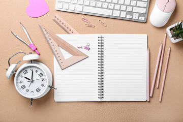 Blank notebook, keyboard and stationery on beige background