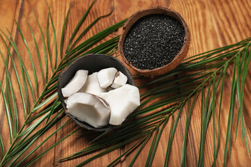 Coconut shells with activated carbon on wooden background