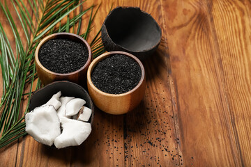 Bowls with coconut activated carbon on wooden background