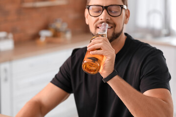 Fototapeta premium Handsome man drinking beer in kitchen