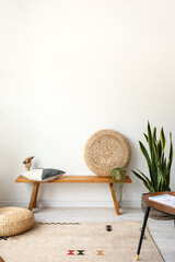 Modern bench with pouf, pillow and wooden hand near light wall