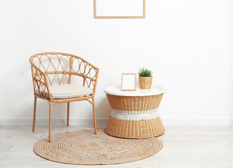 Interior of room with wicker chair and table near light wall