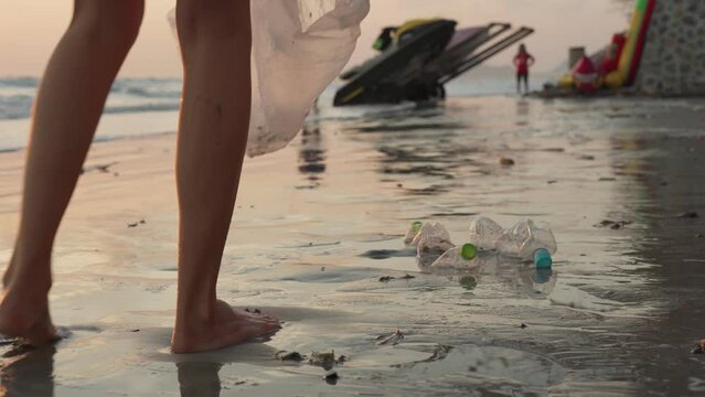 Volunteer picking up trash at the beach. People collect hard-to-decompose plastic bottles to prevent harm to aquatic life. Earth Day or Environment Day. Greening the planet and reduce global warming.