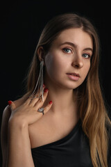 Portrait of young blonde woman with silver jewelry on black background