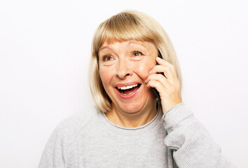 Portrait of attractive senior woman talking by mobile phone over white background