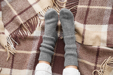 Female legs in warm socks on plaid. Concept of heating season