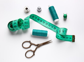Thread spools with measuring tape and scissors on white background