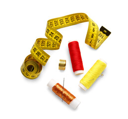 Thread spools with measuring tape and needles on white background