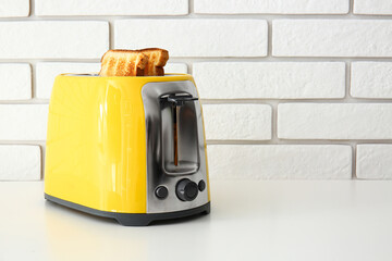 Modern toaster with bread slices on light table