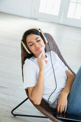 Happy woman with teadphones sitting at chear  at home
