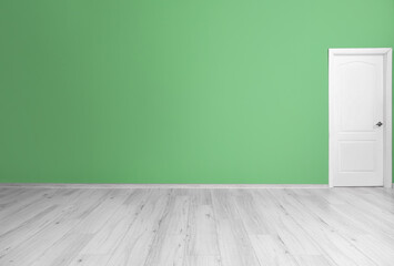 View of green wall with door in big empty room
