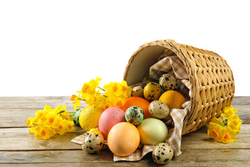 Overturned basket with painted Easter eggs and flowers on table against white background