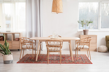 Interior of light dining room with table and vintage carpet