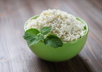 Cottage cheese with mint in a white bowl on a white napkin.