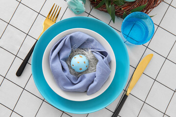 Plate with Easter egg, cutlery and glass on served table