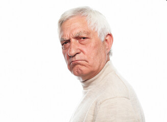 Senior man with gray hair frowns and looks displeased over white background.