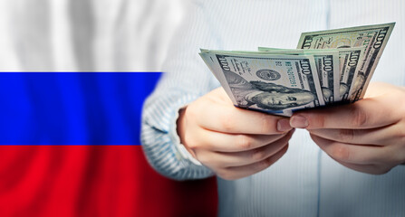 Russian flag and US dollars in hands. Business, tax, banking and finance concept