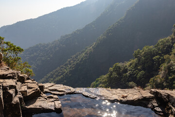 natural swimming pool with dense forests at mountain cliff from top angles