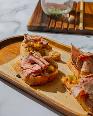 Italian bruschettas with roast beef closeup photo  on marble table on wooden plate with lemonade