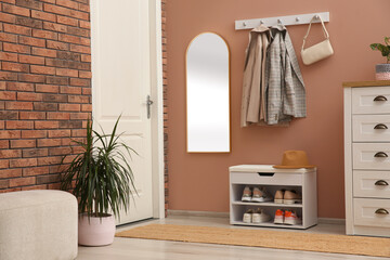 Fototapeta na wymiar Rack with different shoes near pale pink wall in hall