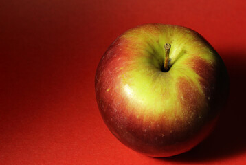 red-yellow apple on a red background close-up