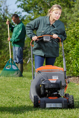 man and woman with lawn mowers working in garden