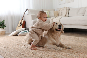 Cute little baby with adorable dog on floor at home