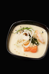 Thai soup with seafood, salmon, tiger shrimp, mussels, hondashi, shiitake mushrooms, togarashi pepper, leeks, sesame seeds. Thai cuisine. Isolated on black background. Close up