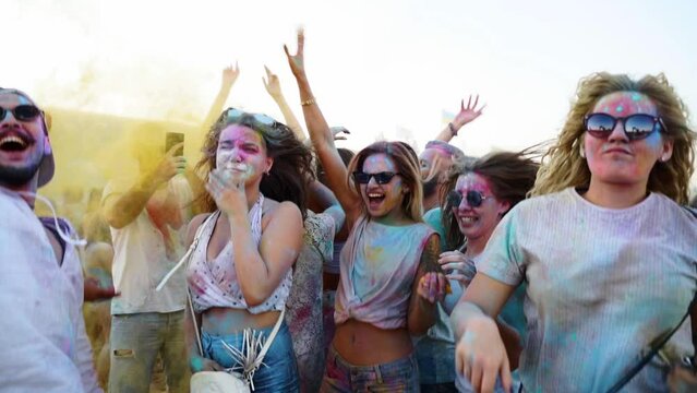 Joyful people smeared in colorful powder have fun, take selfie, play with dry colors to celebrate Holi festival. Outdoor hindu holiday party. End of lockdown, covid pandemic, restrictions.