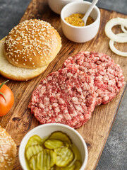 The raw ingredients for the homemade burger. Burger patties. Raw mince meat cutlet, ground beef and pork with bun. Grey background.
