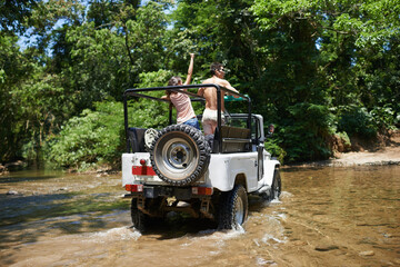 Taking their trip to some extreme terrain. Shot of a young couple driving through a river in their off-road vehicle.