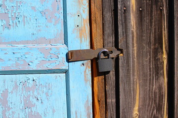 Padlock hanging on old wooden door