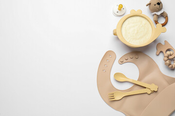 Obraz na płótnie Canvas Healthy baby food in bowl and accessories on white background, top view. Space for text